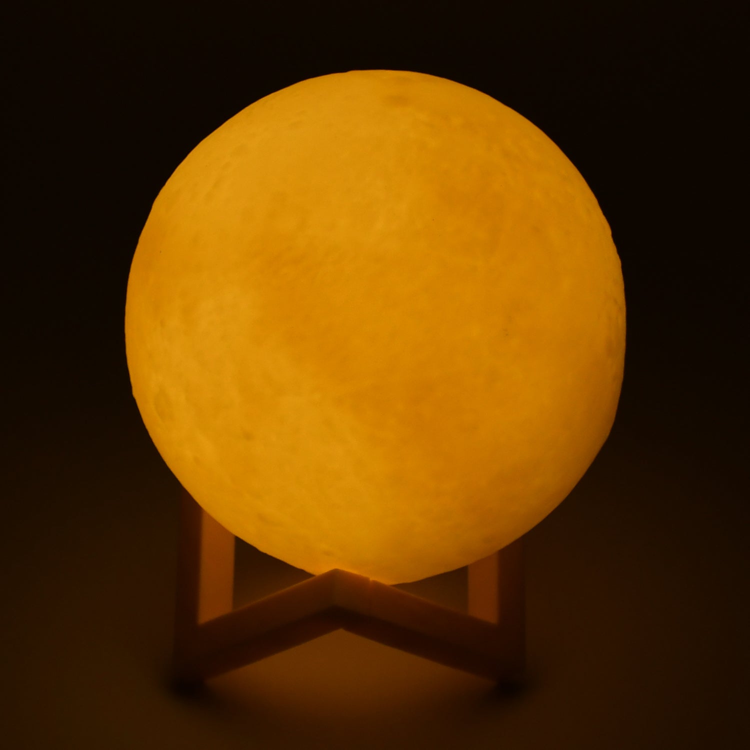 Bedroom nightlight with a moon design and wooden stand.