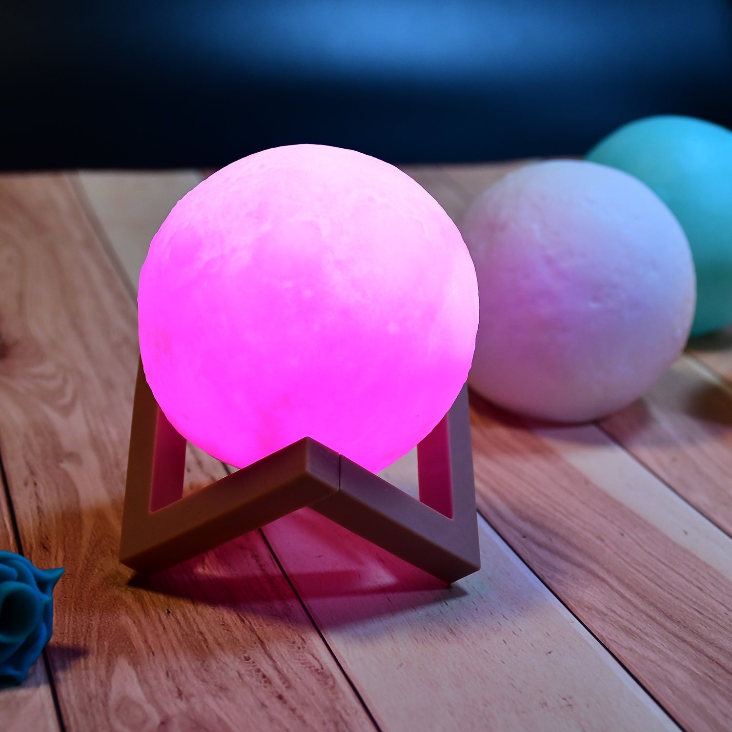 Moon lamp in pink with wooden stand, suitable for bedroom decor.